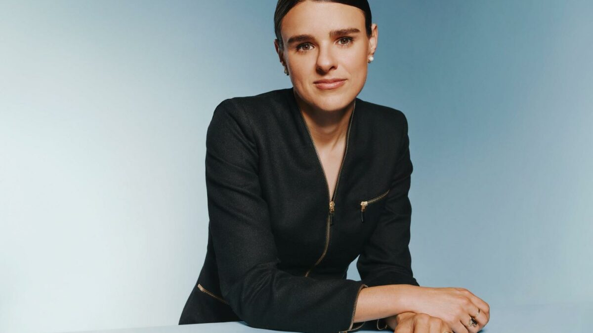 Christina Cacioppo poses while sitting down in a suit jacket