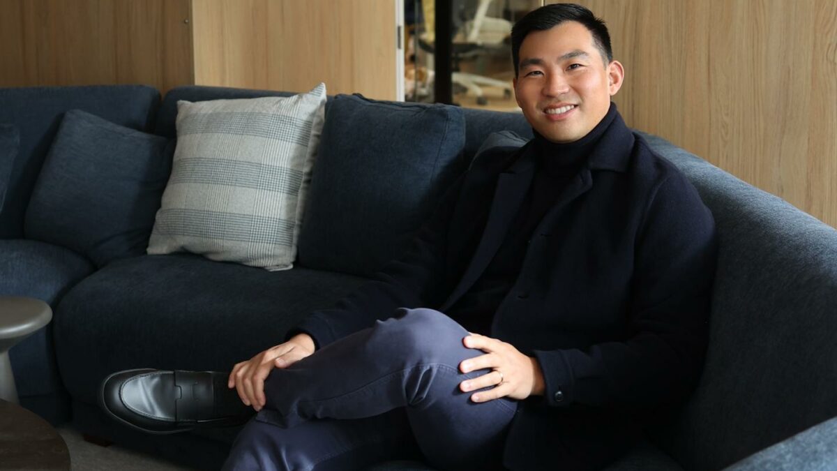 John Zhao smiles and crosses his legs