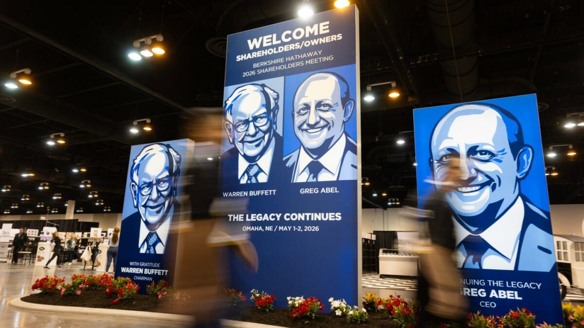 People walk past large portraits of Berkshire Hathaway's Warren Buffett, left, and CEO Greg Abel inside the Berkshire Hathaway annual meeting on Saturday, May 2, 2026, in Omaha, Neb.