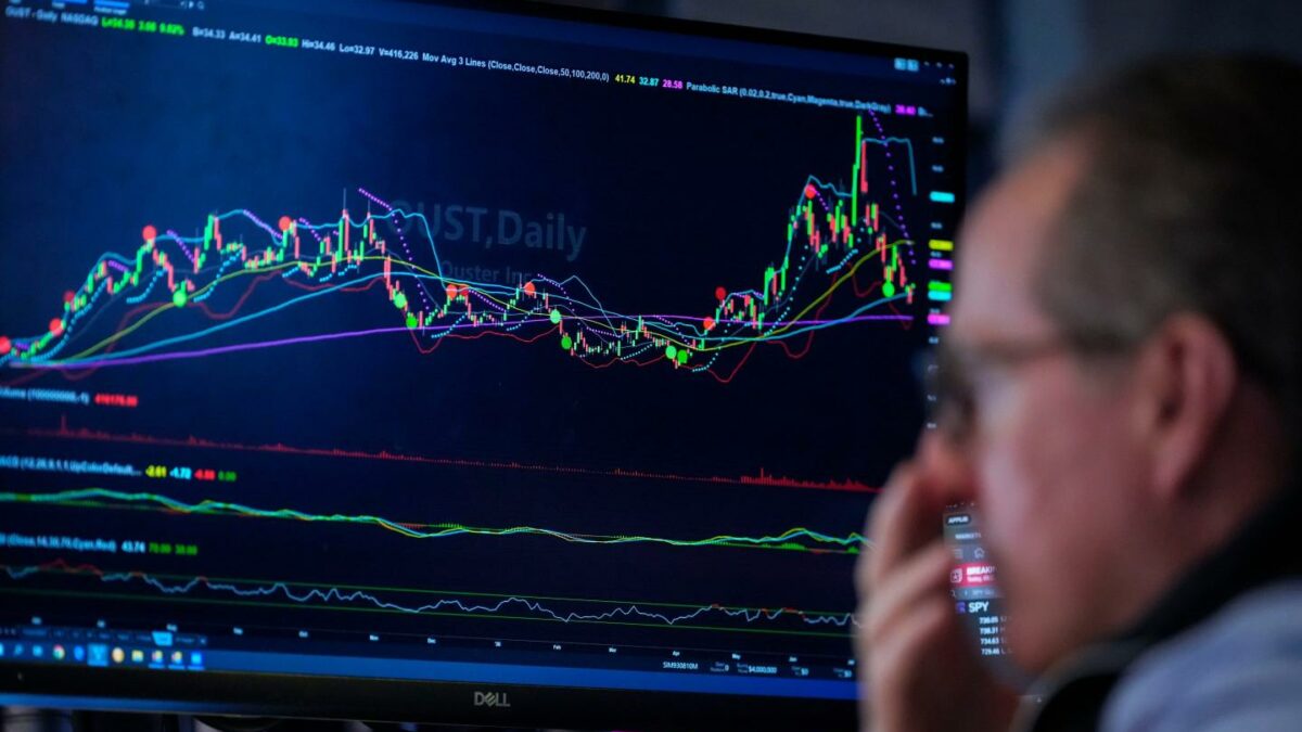 Photo of a trader and a screen showing stocks rallying