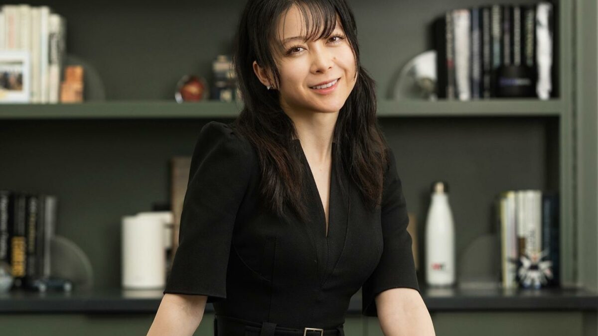 Christina Qi smiles in front of a bookshelf