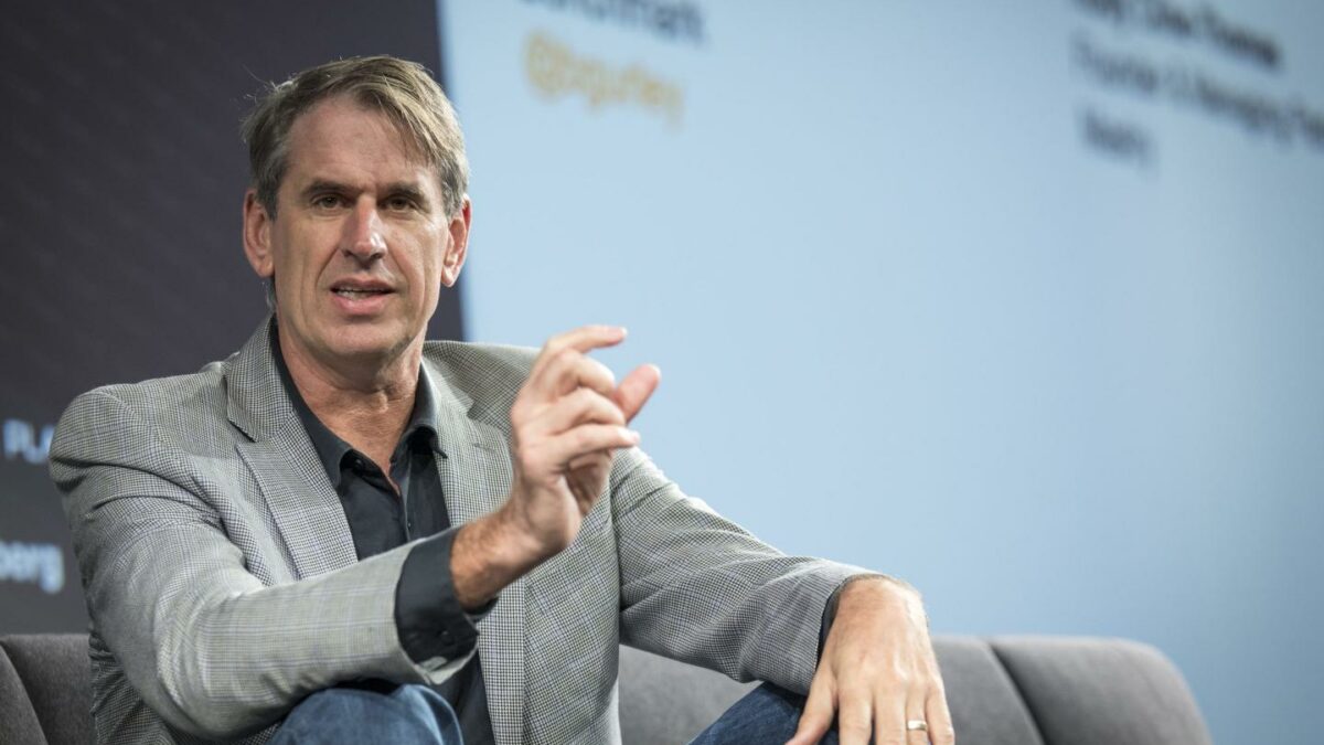 Bill Gurley sits onstage with his arms resting on his knees.