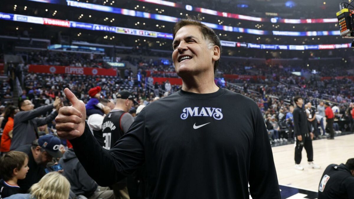 Mark Cuban, standing in a basketball arena, gives a thumbs up.