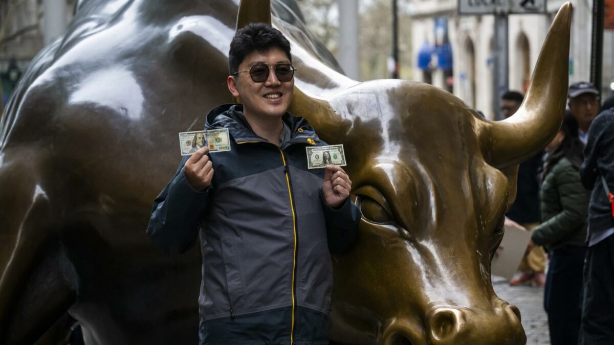 Members of the public pose for photographs beside the Charging Bull, sometimes referred to as the Bull of Wall Street or the Bowling Green Bull on Broadway on April 14, 2025 in New York City.