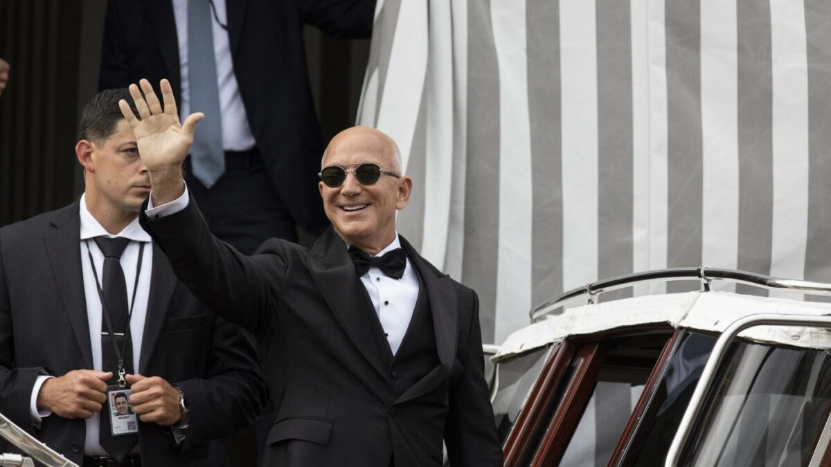 Jeff Bezos waving to a crowd and stepping on to a small boat in Venice