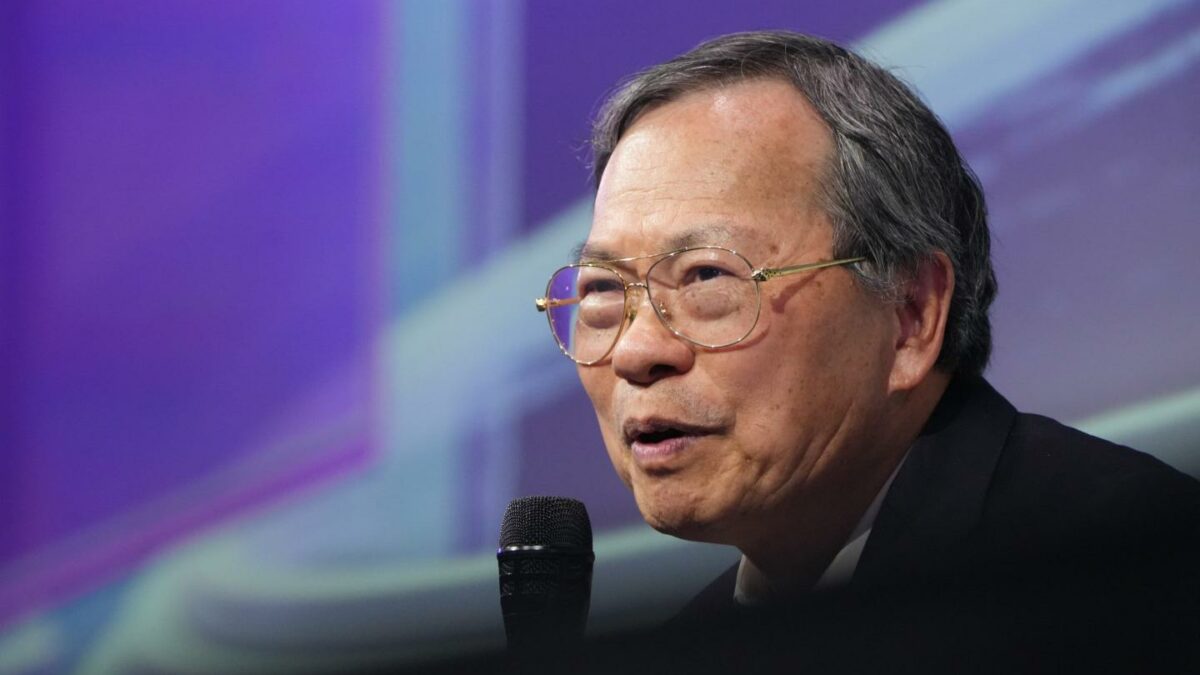 Man with glasses speaking into a microphone