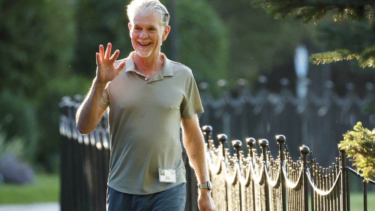 Man in t-shirt and jeans waving while walking