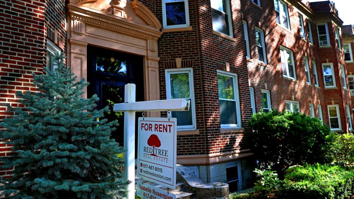 A brick house with a for sale sale in front.