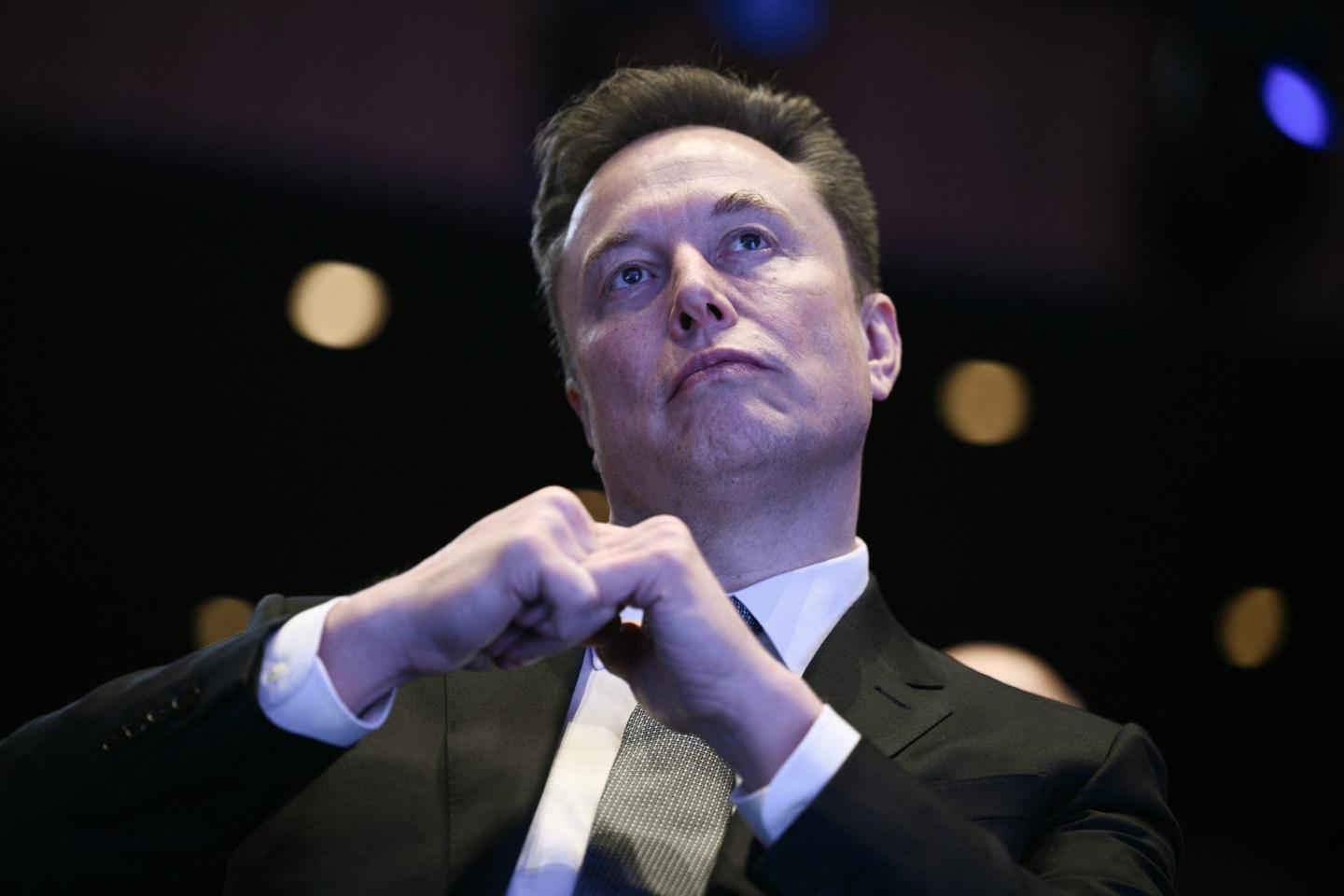 gettyimages-2246892016-e1778691314221 Elon Musk sits with his fists together, looking up.