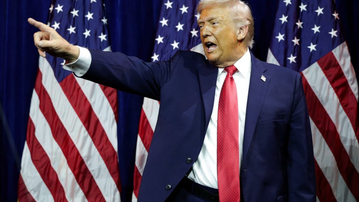 President Donald Trump pointing in front of American flags.