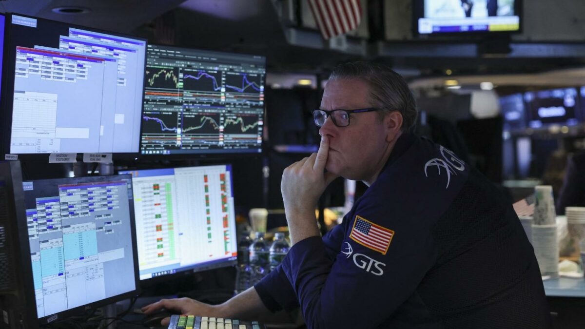 A trader at the New York Stock Exchange looks at screens while appearing concerned
