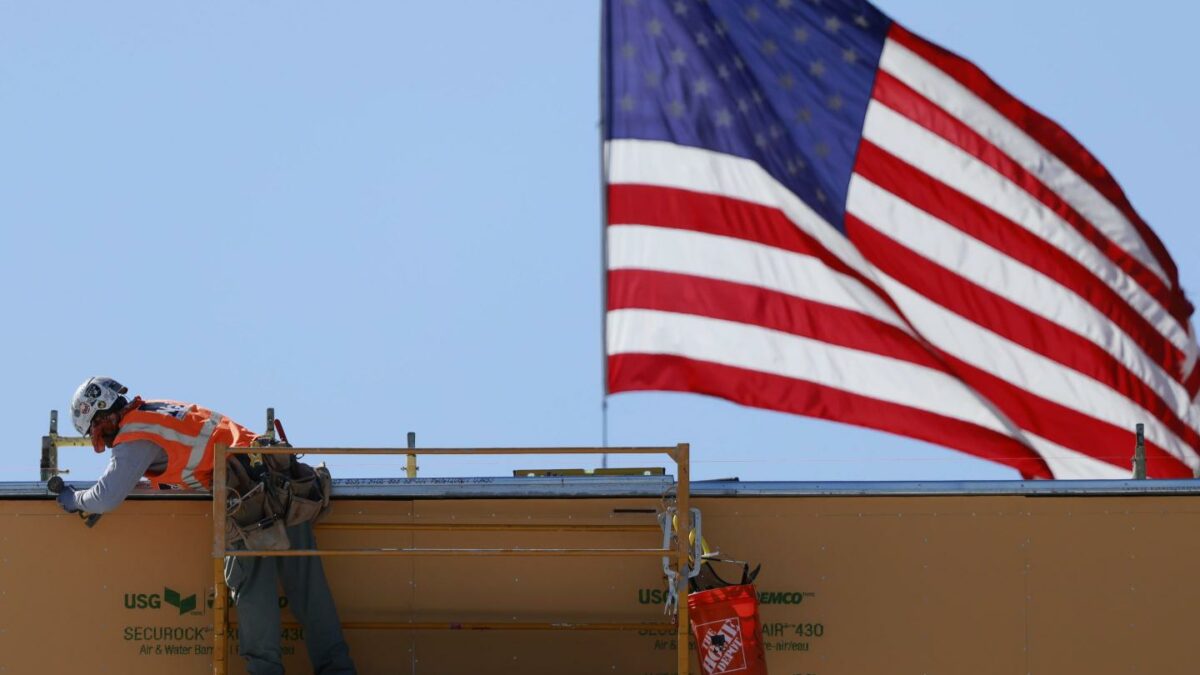 An American flag flies near a construction worker during construction of a new building on March 6, 2026 in Pasadena, California.