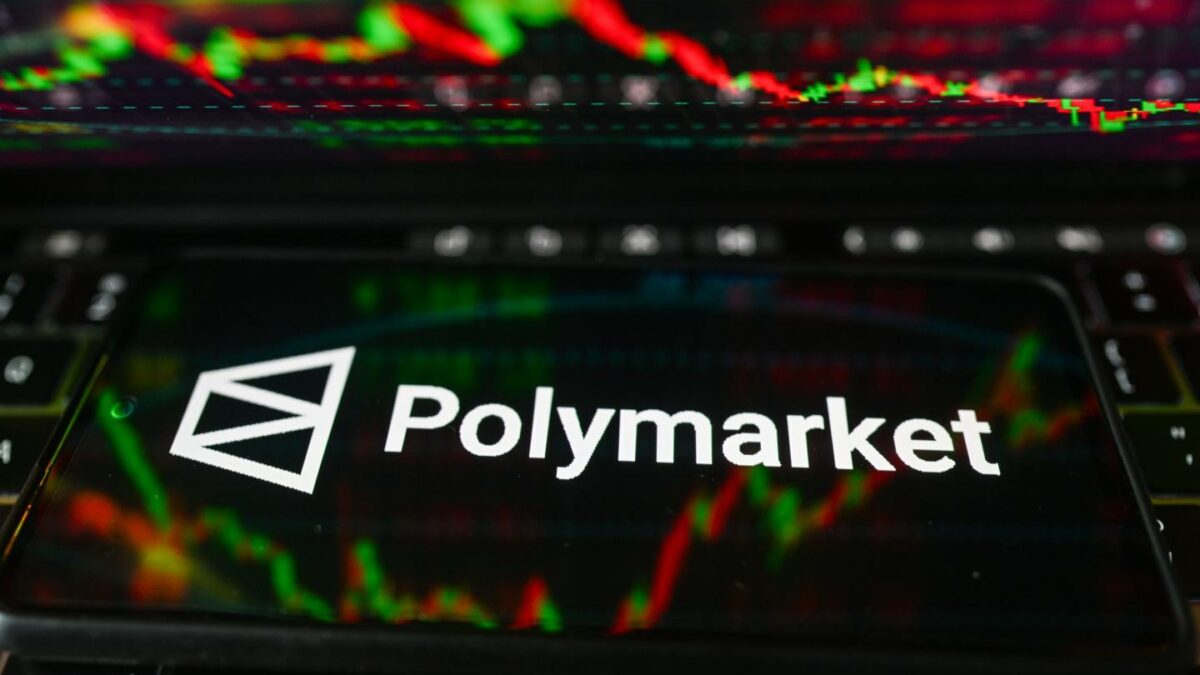 POLAND - 2026/03/16: In this photo illustration, the Polymarket logo is displayed on a smartphone with stock market percentages in the background. (Photo Illustration by Omar Marques/SOPA Images/LightRocket via Getty Images)