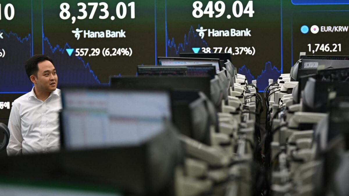 A currency dealer walks past an electronic screen showing South Korea's benchmark stock index (KOSPI) in a foreign exchange dealing room at the Hana Bank headquarters in Seoul on June 26, 2026.