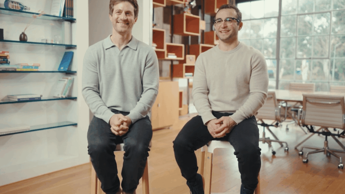 Nick Noone and Ben Rudolph sit on stools